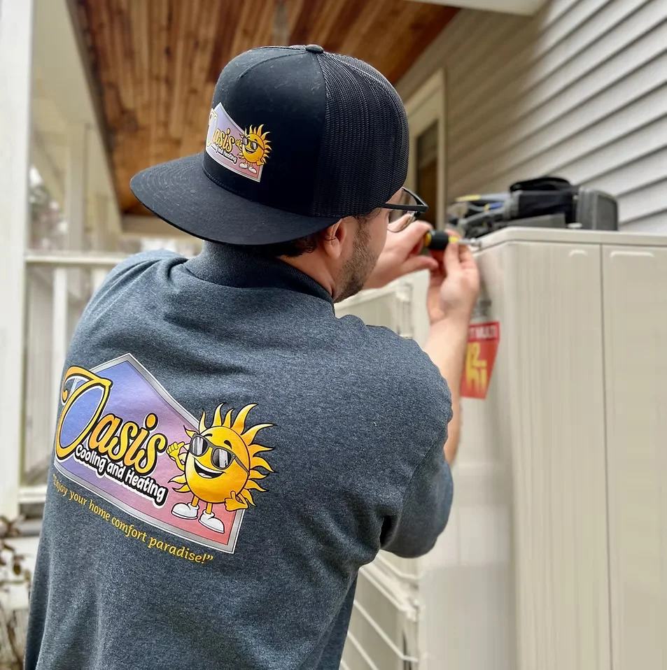 Oasis technician in branded gear servicing an outdoor HVAC unit